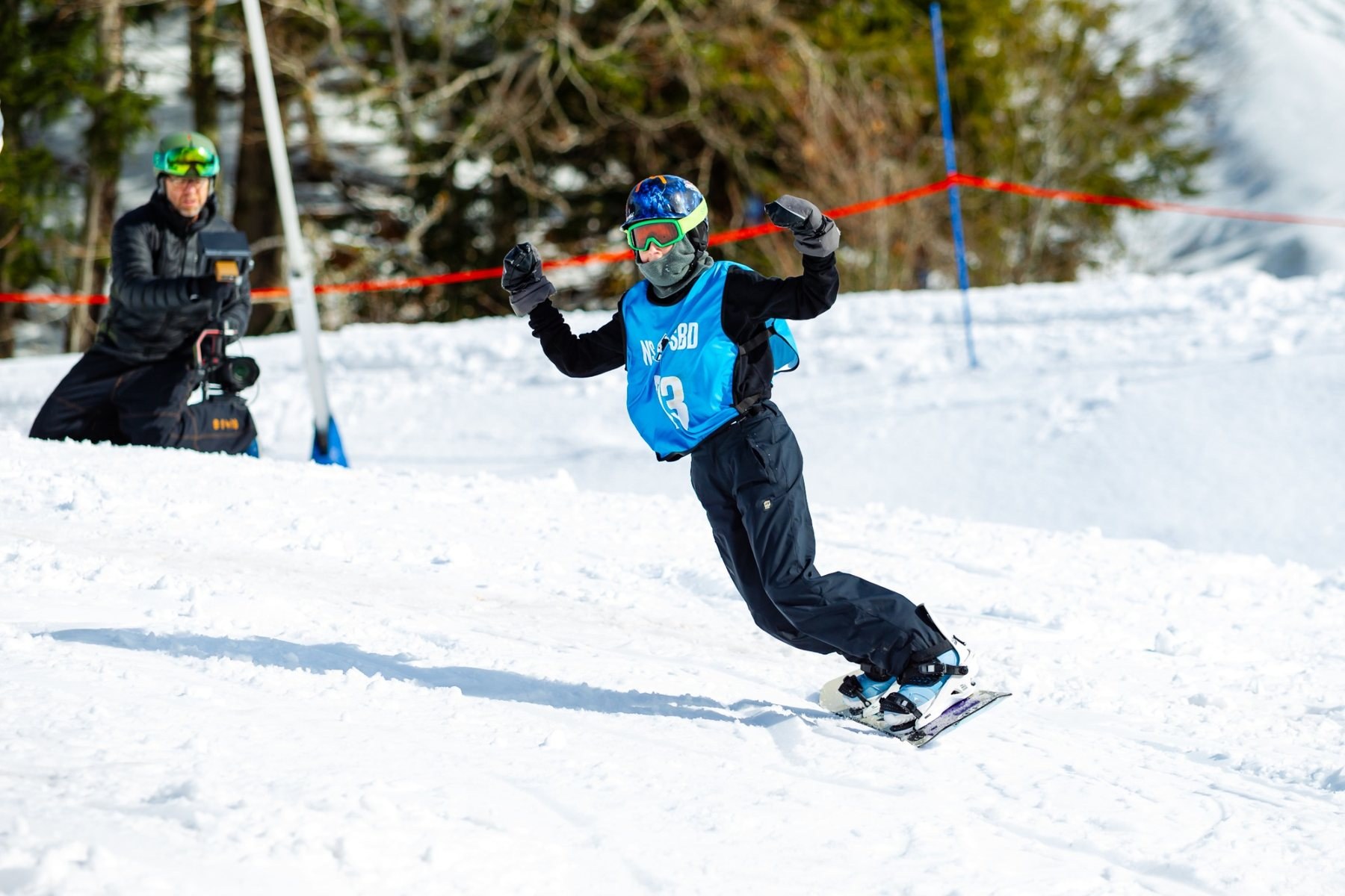 Snowboarder progressing through a course with coaching nearby